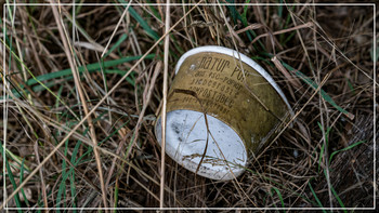 weggeworfener Pappbecher, der im Gras liegt