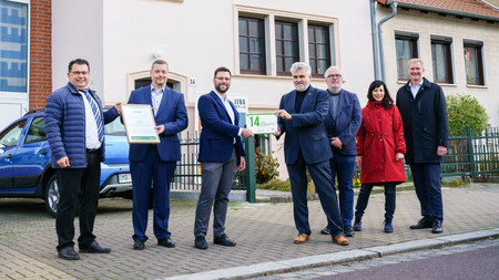 Prof. Dr. Armin Willingmann, Minister für Wissenschaft, Energie, Klimaschutz und Umwelt des Landes Sachsen-Anhalt, übergibt eine „Grüne Hausnummer Sachsen-Anhalt“ an Familie Wendler aus der Landeshauptstadt Magdeburg