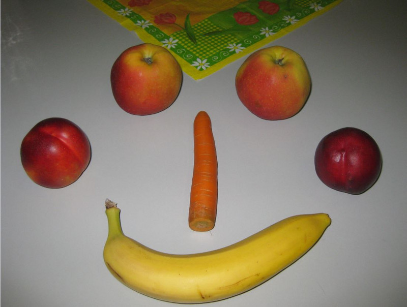 Äpfel, Banane, Möhre und Pfirsiche als Gesicht angeordnet