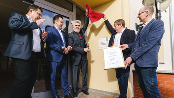 Minister Willingmann enthüllt das Schild mit der Aufschrift "Kommune mit ausgezeichnetem Energiemanagement", das am Verwaltungsamt der Verbandsgemeinde Mansfelder Grund-Helbra angebracht wurde.