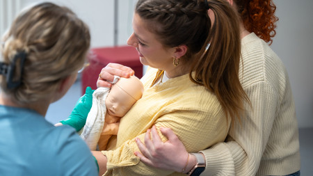 Studierende simulieren ein Szenario, in dem eine aufrechte Geburt unterstützt werden soll.